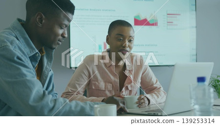 Analyzing data office colleagues reviewing laptop in meeting room, with coffee mugs, chart display Analyzing data office colleagues reviewing laptop in meeting room, with coffee mugs, chart display 139253314