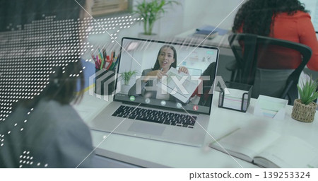 Remote businesswoman wearing gray blazer showing charts in office, with laptop, pencil cup, plant Remote businesswoman wearing gray blazer showing charts in office, with laptop, pencil cup, plant 139253324