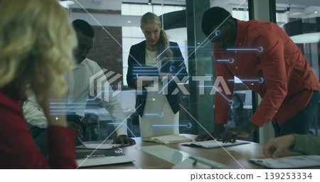 Collaborating team reviewing project plans around boardroom table with holographic interface Collaborating team reviewing project plans around boardroom table with holographic interface 139253334