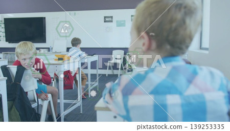 Elementary school boys writing on papers at white desks in classroom, with flat-screen display Elementary school boys writing on papers at white desks in classroom, with flat-screen display 139253335