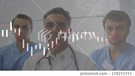 Doctor and nurses analyzing candlestick overlay in clinic corridor, with stethoscope, scrubs 139253351