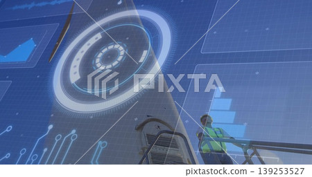 Worker wearing safety vest and hat examining digital interface on platform at job site, copy space 139253527