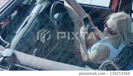 Leaning back woman with sunglasses, resting legs on dashboard inside parked car, holding smartphone Leaning back woman with sunglasses, resting legs on dashboard inside parked car, holding smartphone 139253568