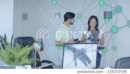 Gesturing business casual coworkers using smartphone and tablet in office with robotic hand graphic Gesturing business casual coworkers using smartphone and tablet in office with robotic hand graphic 139253590