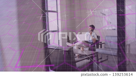 Remote worker holding smartphone to ear and balancing laptop in home lounge, coffee mug, copy space 139253614
