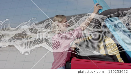 Lifting woman wearing pink shirt placing blue tube into red car trunk in parking bay Lifting woman wearing pink shirt placing blue tube into red car trunk in parking bay 139253632