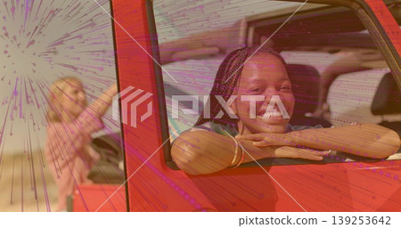 Leaning women smiling through red off-road vehicle windows on sandy plain, bracelets, copy space 139253642