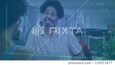 Curly-haired man talking to female colleague in open-plan office, with monitors and chart overlay Curly-haired man talking to female colleague in open-plan office, with monitors and chart overlay 139253677
