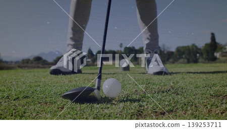 Male golfer aligning driver behind golf ball on tee box at golf course, with beige pants Male golfer aligning driver behind golf ball on tee box at golf course, with beige pants 139253711