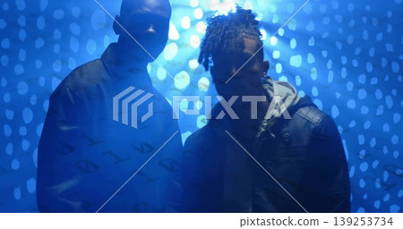 Standing two men wearing leather jacket over hoodie and dark sweatshirt in studio, blue dot pattern 139253734