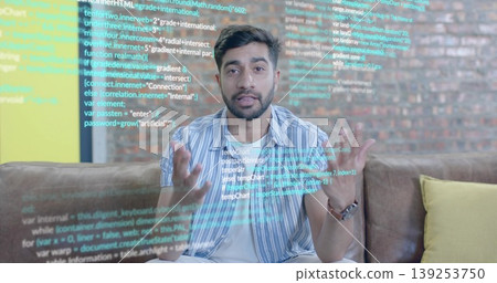 Gesturing Indian man at floating computer code in modern lounge, with brown upholstered sofa Gesturing Indian man at floating computer code in modern lounge, with brown upholstered sofa 139253750