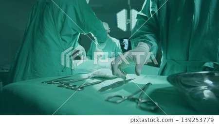 Reaching gloved surgeon's hand selecting scalpel on draped tray under lights in operating room Reaching gloved surgeon's hand selecting scalpel on draped tray under lights in operating room 139253779