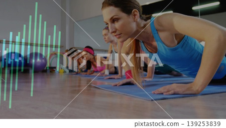 Instructor in tank top leading group doing push-ups on mats in fitness studio with Swiss balls Instructor in tank top leading group doing push-ups on mats in fitness studio with Swiss balls 139253839