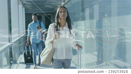 Walking travelers in formal wear carrying suitcases and coffee through airport walkway, reflections 139253928