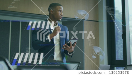 Reviewing man wearing suit holding tablet analyzing charts in conference room, with data overlays Reviewing man wearing suit holding tablet analyzing charts in conference room, with data overlays 139253978