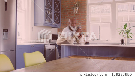 Leaning senior African American man sipping coffee at home kitchen island, with French press mug Leaning senior African American man sipping coffee at home kitchen island, with French press mug 139253990
