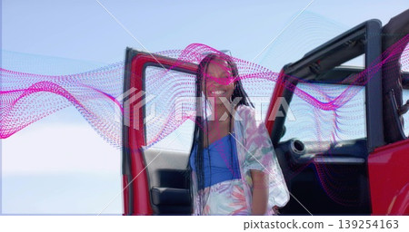 Woman in blue tank and shorts stepping out of red SUV by seaside, with pink-wave overlay Woman in blue tank and shorts stepping out of red SUV by seaside, with pink-wave overlay 139254163