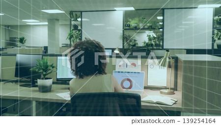 Watching office professional analyzing charts on laptop and dual monitor at cubicle desk Watching office professional analyzing charts on laptop and dual monitor at cubicle desk 139254164