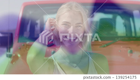 Standing blonde woman wearing sleeveless top in sunny parking lot, with red SUV backdrop 139254175