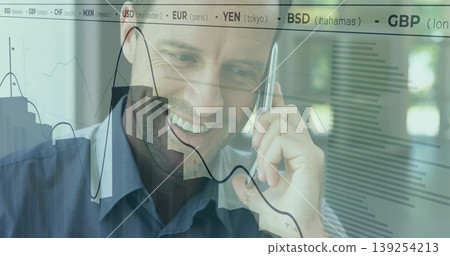 Smiling professional holding smartphone to ear near office window, with financial charts and ticker Smiling professional holding smartphone to ear near office window, with financial charts and ticker 139254213