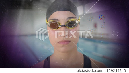 Focusing competitive swimmer standing at pool edge, with black swim cap and yellow-tinted goggles Focusing competitive swimmer standing at pool edge, with black swim cap and yellow-tinted goggles 139254243