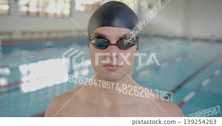 Standing swimmer wearing black swim cap and goggles poolside, showing digital metrics, lane ropes 139254263