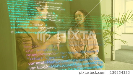 Two software professionals discussing code overlay on sofa in office lounge, with mug and tablet Two software professionals discussing code overlay on sofa in office lounge, with mug and tablet 139254323