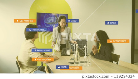 Gesturing woman wearing blazer and holding solar panel toward wind turbine in meeting room Gesturing woman wearing blazer and holding solar panel toward wind turbine in meeting room 139254324