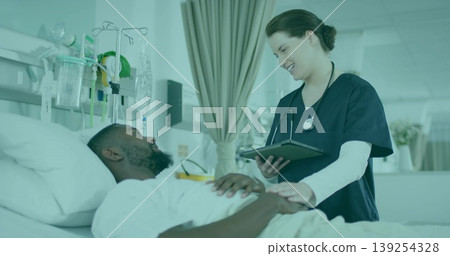 Female nurse in scrubs holding tablet and touching patient in ward, with IV pole, copy space Female nurse in scrubs holding tablet and touching patient in ward, with IV pole, copy space 139254328