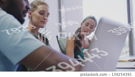Three professionals analyzing numeric data on laptop in conference room with coffee cup, notebooks Three professionals analyzing numeric data on laptop in conference room with coffee cup, notebooks 139254391