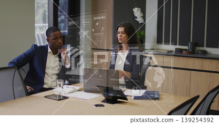 Two business professionals reviewing data projections in conference room, with laptop overlays 139254392