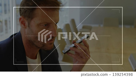 Sitting adult male speaking into smartphone at wooden table in boardroom, with chairs, copy space Sitting adult male speaking into smartphone at wooden table in boardroom, with chairs, copy space 139254398