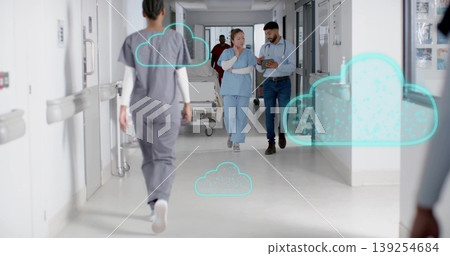 Walking co-workers in scrubs and business shirts using tablet in hospital hallway, with cloud icons Walking co-workers in scrubs and business shirts using tablet in hospital hallway, with cloud icons 139254684