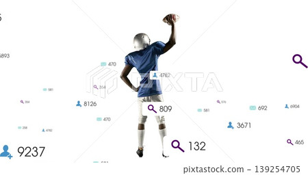 Raising helmeted, jersey-clad football player gripping football overhead amid data icons on white 139254705