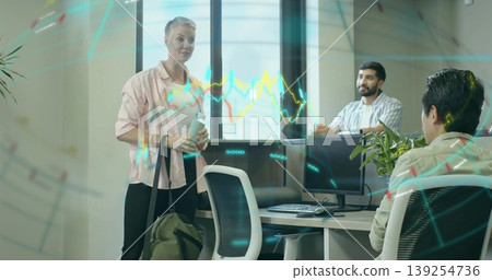 Woman in pink top and coworkers discussing work in open-plan office at desk with computer monitor Woman in pink top and coworkers discussing work in open-plan office at desk with computer monitor 139254736