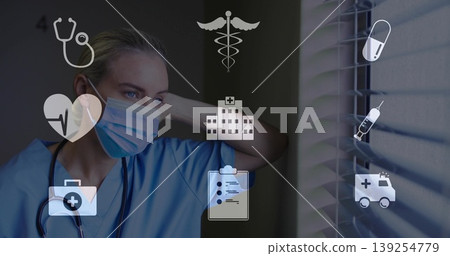 Leaning worker in scrubs mask stethoscope gazing through blinds in clinic overlaid medical icons Leaning worker in scrubs mask stethoscope gazing through blinds in clinic overlaid medical icons 139254779