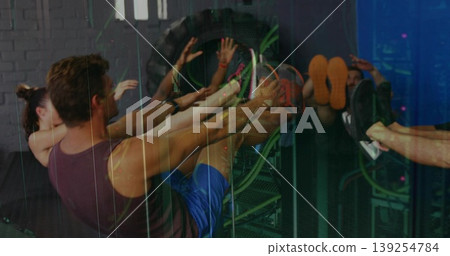 Friends performing leg raises on benches in gym wearing sportswear with tractor tire, copy space Friends performing leg raises on benches in gym wearing sportswear with tractor tire, copy space 139254784