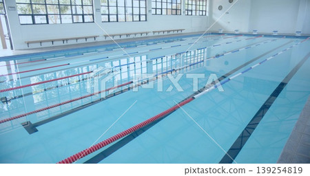 Empty lap pool occupying central pool hall, with red and blue lane dividers and wooden bench Empty lap pool occupying central pool hall, with red and blue lane dividers and wooden bench 139254819