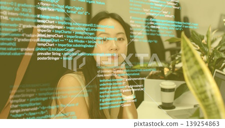 Analyzing transparent code display, Asian female sitting at office desk, with coffee cup and plant 139254863