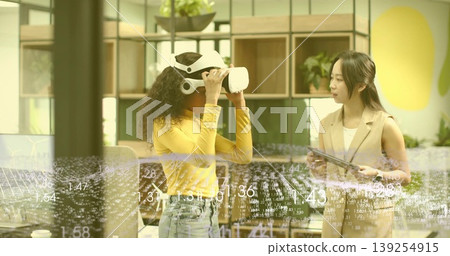 Testing man wearing virtual reality headset engaging in modern office space, with tablet and plants Testing man wearing virtual reality headset engaging in modern office space, with tablet and plants 139254915