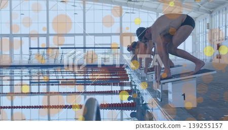 Positioning male swimmers with caps goggles crouching on starting blocks on pool deck, copy space 139255157