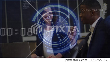 Reviewing sales data, executives collaborating at office desk in suits with laptop, HUD overlay 139255187
