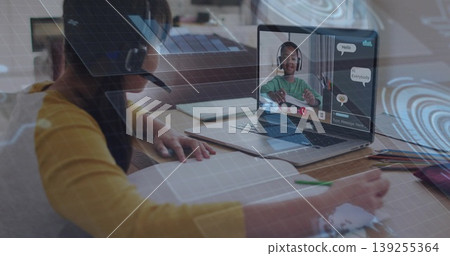 Sitting girl wearing headset writing notebook at home, with laptop showing classmate, pencils Sitting girl wearing headset writing notebook at home, with laptop showing classmate, pencils 139255364