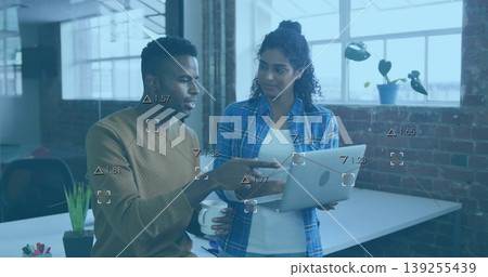 Reviewing data visualization, two coworkers standing by desk at office, with laptop and coffee mug Reviewing data visualization, two coworkers standing by desk at office, with laptop and coffee mug 139255439