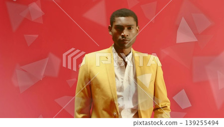 Standing mid adult man wearing yellow blazer and white shirt in studio, with geometric triangles Standing mid adult man wearing yellow blazer and white shirt in studio, with geometric triangles 139255494