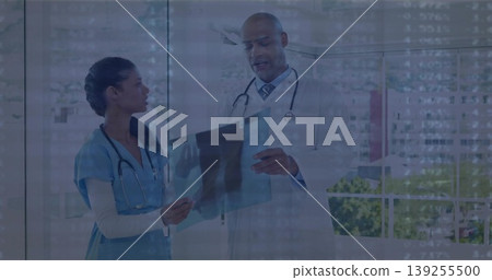 Nurse in scrubs and doctor in lab coat reviewing X-ray film in consultation room, two stethoscopes Nurse in scrubs and doctor in lab coat reviewing X-ray film in consultation room, two stethoscopes 139255500