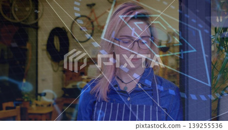 Standing woman wearing striped apron and glasses at bicycle shop, with digital overlays and tools Standing woman wearing striped apron and glasses at bicycle shop, with digital overlays and tools 139255536