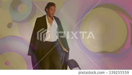 Standing male model wearing black blazer and open white shirt in studio, with projected light rings Standing male model wearing black blazer and open white shirt in studio, with projected light rings 139255539