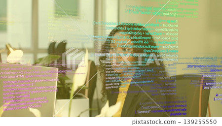 Typing coder writing code on monitor at office desk, with plant, lamp and code overlay Typing coder writing code on monitor at office desk, with plant, lamp and code overlay 139255550