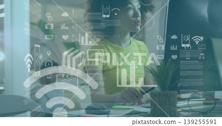 Analyzing woman wearing yellow top monitoring network data at office desk, with overlay graphics Analyzing woman wearing yellow top monitoring network data at office desk, with overlay graphics 139255591